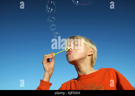 Ragazzo di piccole bolle contro un profondo cielo blu Foto Stock