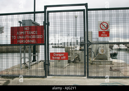 Recinzione e cartelli di avvertimento è vietato al personale non autorizzato pericolo tenere spento e non immersione sulla banchina a annalong Harbour Foto Stock