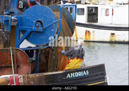 Fisherman esaminando le reti sulla bobina sul retro del suo peschereccio per traino Kilkeel Harbour contea di Down Irlanda del Nord Foto Stock