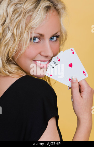 Una giovane e bella donna bionda sorridente con una mano di 4 assi Foto Stock