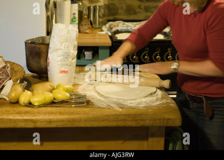 Foto di stock di impasto per pizza essendo arrotolato su un tavolo da cucina Foto Stock