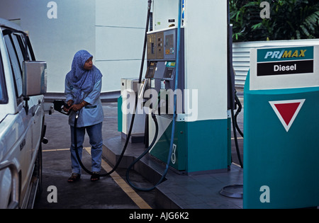 Femmina pompa benzina attendant riempimento auto con carburante, Malaysia Asia SE Foto Stock