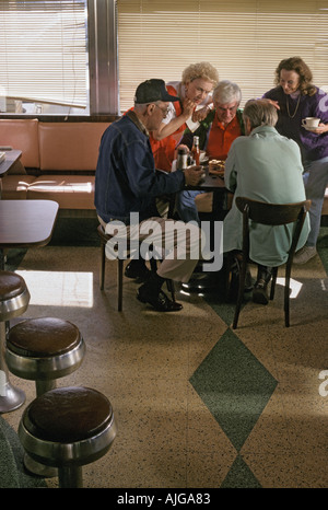 Seniors caucasica riuniti intorno ad un tavolo e giocare il gioco della dama in un diner Foto Stock