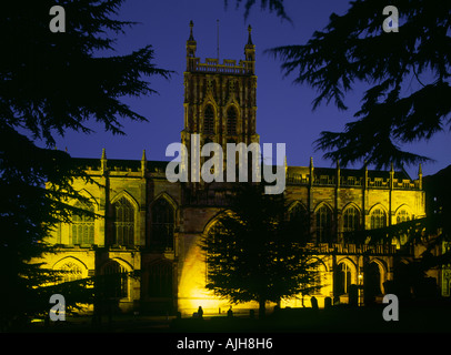 Malvern Priory di notte illuminata da luce artificiale, incorniciato da alberi, Great Malvern, Worcestershire, Inghilterra. Foto Stock