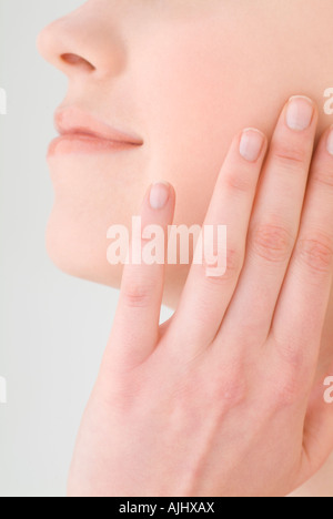 Giovane donna di toccare la sua guancia, close-up Foto Stock