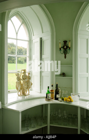 Incassato nella finestra gotica con persiane e vetreria scaffale con bottiglie di bevande Foto Stock