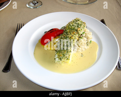 Cuocere il pesce al forno in crosta di ippoglosso oltre il risotto su un piatto di portata in ceramica bianca Foto Stock