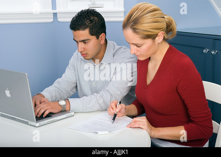 Giovani indiani maschio e femmina bianca di studente universitario di studio per la scuola utilizzando un computer Mac portatile Foto Stock
