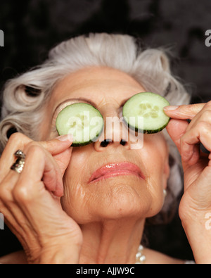Un senior donna azienda cetrioli sopra gli occhi Foto Stock