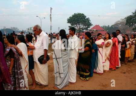 I devoti la condivisione di un momento di luce mentre erano in attesa in una coda per il darshan al di fuori di un tempio di Aluva, Kerala Foto Stock