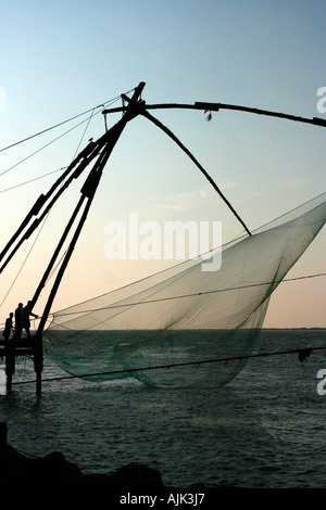 Reti cinesi essendo sollevata da un gruppo di pescatori a Cochin, Kerala Foto Stock