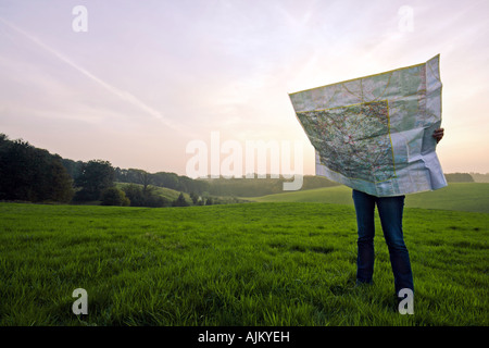 Persona persa in piedi sul prato verde tenendo un grande roadmap a tramonto Foto Stock