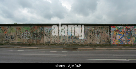 Sezione verniciata del muro di Berlino al lato est sotto un cielo nuvoloso in un giorno di pioggia Foto Stock