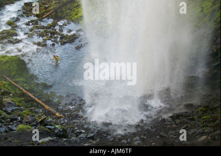 Un uomo escursionismo acrossing un flusso al di sotto di una cascata nei pressi del Monte Cofano o Foto Stock