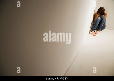 Ragazza rannicchiato in angolo Foto Stock