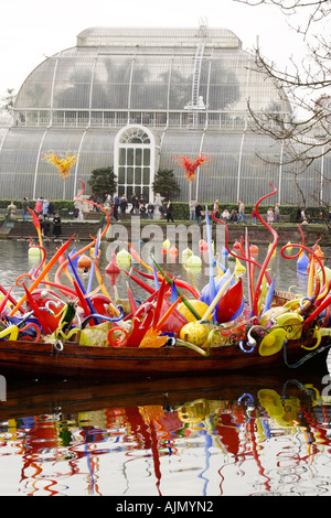 Chihuly vetro soffiato scultura su una barca galleggianti in un lago esposti al Kew Gardens, Londra. Conservatorio in background Foto Stock