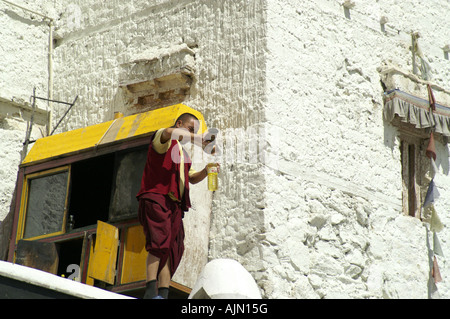 Il Tibetano monaco buddista uomo versando brucia olio nella lampada luce nel monastero di Spitok Leh Ladakh India Foto Stock