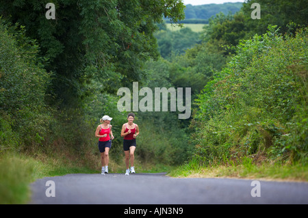 Due donne jogging su un vicolo del paese nr Charlton Horethorne Somerset England Regno Unito MR Foto Stock