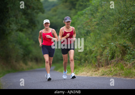 Due donne jogging su un vicolo del paese nr Charlton Horethorne Somerset England Regno Unito MR Foto Stock