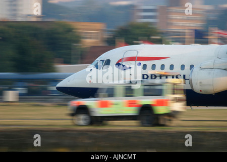 British Airways jet commerciale passando dietro il personale a terra Land Rover durante il decollo aeroporto della città di Londra, Inghilterra, Regno Unito Foto Stock