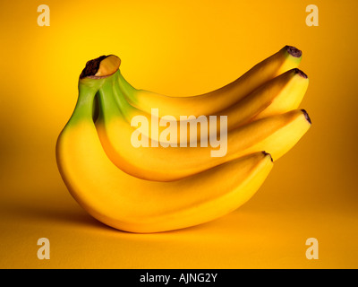 Un grappolo di banane gialle su una corrispondente sfondo giallo Foto Stock