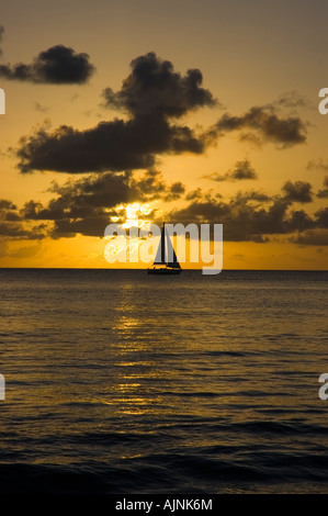 Barca a vela stagliano contro il sole di setting off l'isola caraibica di Barbados Foto Stock