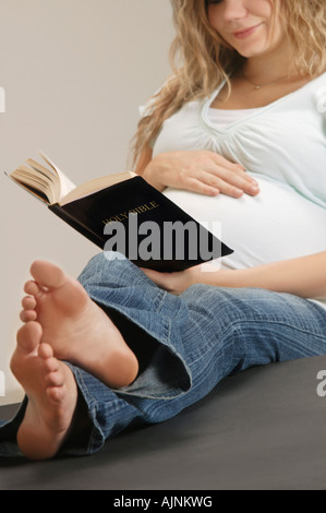 Una donna in stato di gravidanza della lettura della Bibbia Foto Stock