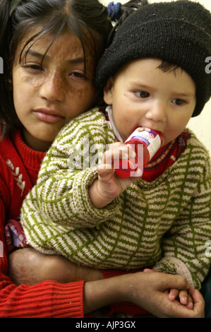 Bambino indiano kid ragazza con bambino bere latte dalla bottiglia abbraccio con amore Foto Stock