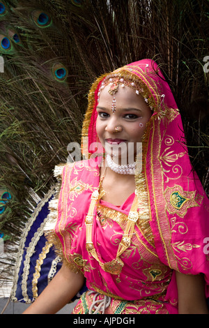 Una donna in rosa e oro costume di Rajasthani con penne di pavone, in un corteo durante il Festival di elefante a Jaipur, Rajasthan, India. Foto Stock