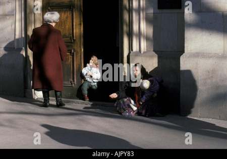 Donna gitana e figli mendicare al di fuori di una chiesa a Bratislava centro città della Slovacchia Foto Stock