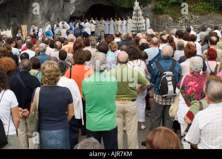 Pellegrini pregano e ottenere benedizioni nella parte anteriore della grotta, la cattedrale di Notre Dame di Lourdes Foto Stock