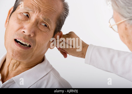 Close-up di un senior donna tenendo un anziano uomo l orecchio Foto Stock