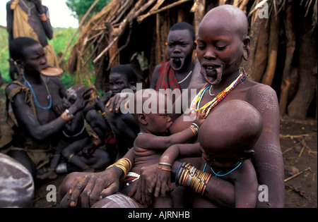 Surma donna allattare al seno il suo bambino, a ovest del fiume Omo Etiopia Foto Stock