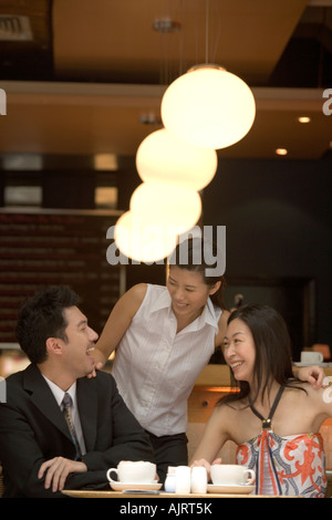 Due giovani donne con un giovane uomo in un ristorante Foto Stock