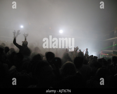 Frequentatori di partito agitare le mani in aria come luci laser il flusso attraverso la camera a un rave dance party. Foto Stock
