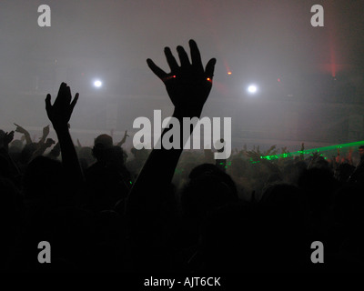 Frequentatori di partito agitare le mani in aria come luci laser il flusso attraverso la camera a un rave dance party. Foto Stock