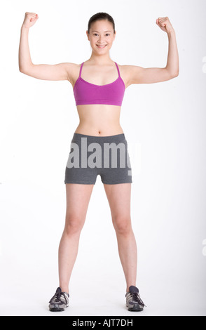 Ritratto di una giovane donna flettendo la sua muscolatura e sorridente Foto Stock
