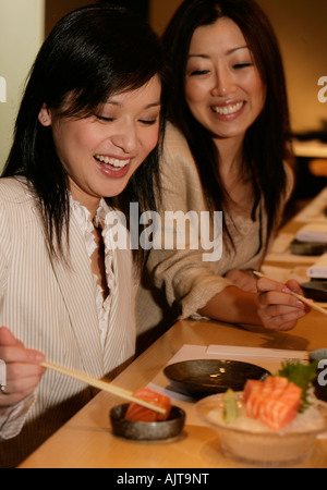 Due imprenditrici mangiare sushi con bacchette Foto Stock