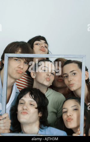 Un gruppo di giovani amici che posano per una foto, tenendo su Picture Frame, raggrinzimento in telecamera, ritratto Foto Stock