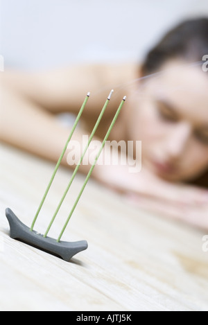 Donna sdraiata testa in appoggio sui bracci, concentrarsi su bruciare incenso in primo piano Foto Stock