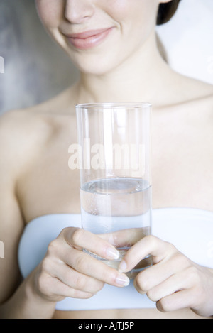 Vista ritagliata della donna di vetro di contenimento di acqua, sorridente Foto Stock