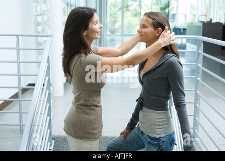 La madre e la ragazza adolescente insieme, donna spingendo figlia indietro i capelli, vista laterale Foto Stock