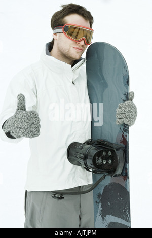 Giovane maschio snowboarder, dando pollice in alto segno alla fotocamera Foto Stock