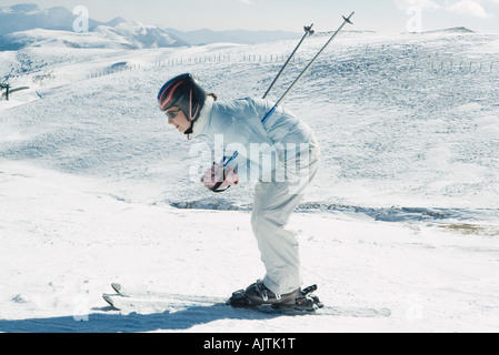 Giovane sciatore chinarsi, vista laterale a piena lunghezza ritratto Foto Stock