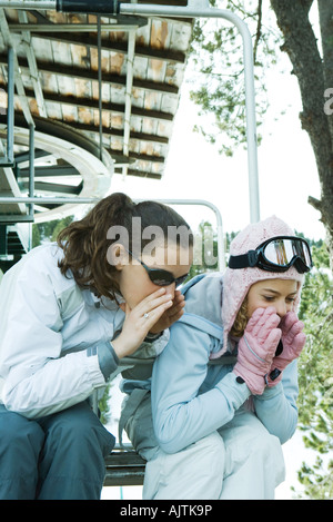 Le ragazze adolescenti seduti su una sedia lift insieme, sporgendoti, urlando Foto Stock