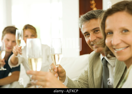 Amici adulti facendo un brindisi con champagne, sorridente in telecamera Foto Stock