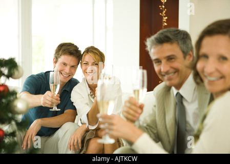 Amici adulti facendo un brindisi con champagne, sorridente in telecamera Foto Stock