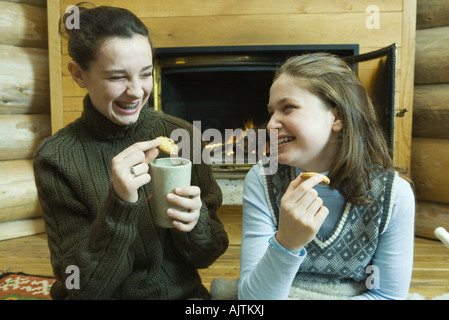 Le ragazze adolescenti avente uno snack da camino, ridendo Foto Stock