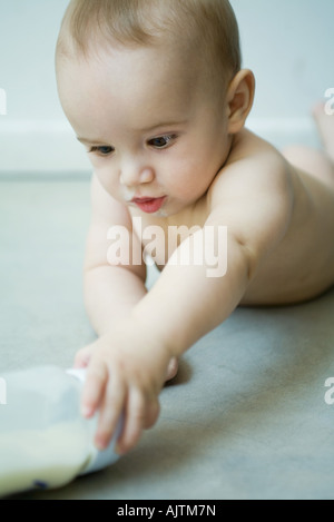 Il Bambino giacente sul piano, raggiungendo per bottiglia Foto Stock