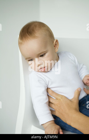 Baby sitting in cattedra, madre di mani del bambino alla cintura Foto Stock